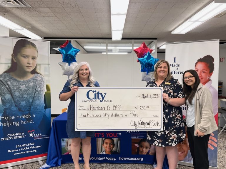 Three people stand behind a large ceremonial check presented by City National Bank