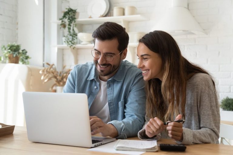 Couple looking at laptop together in kitchen