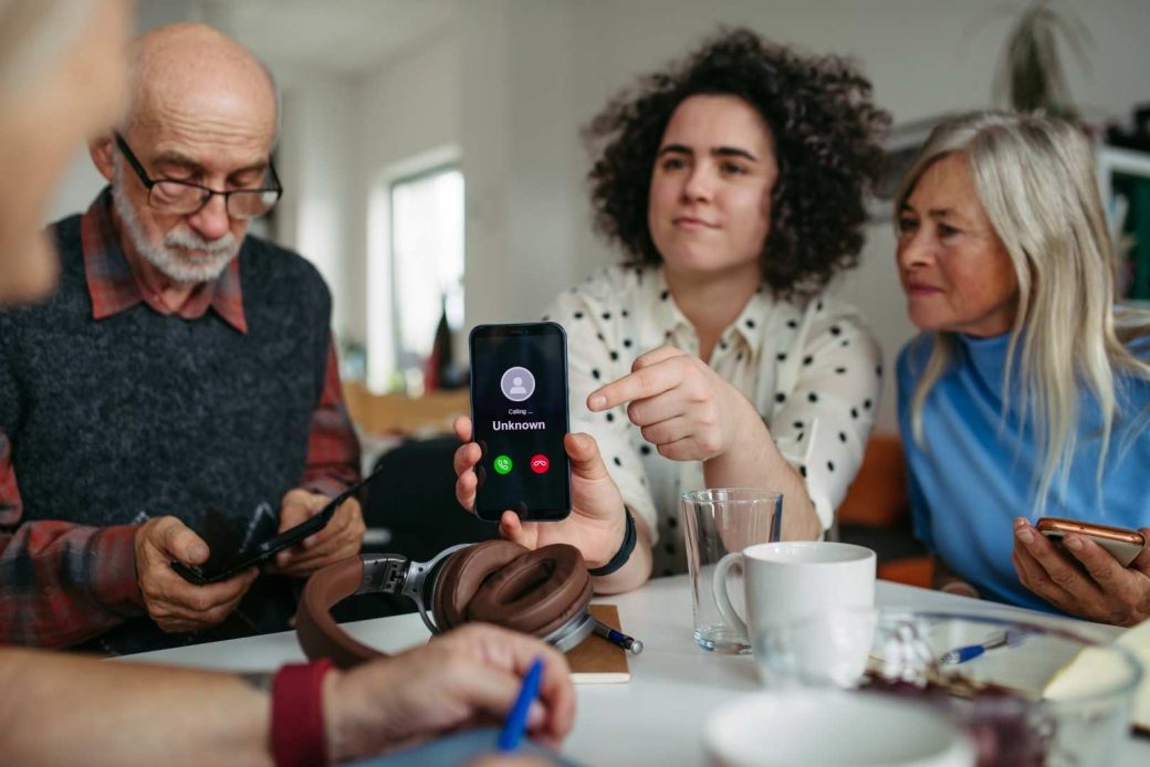 A person points to a smartphone displaying an incoming call from an unknown number