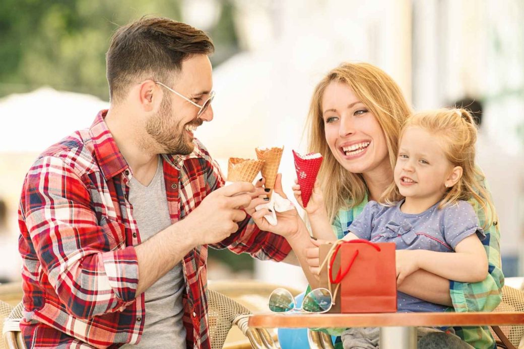 A smiling family enjoying ice cream cones outdoors.